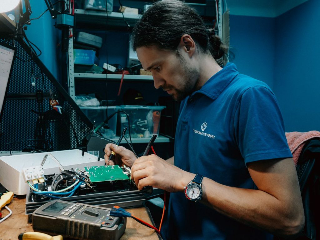 Technician working on a circuit board in a well-equipped workshop, showcasing technical skills and precision.
